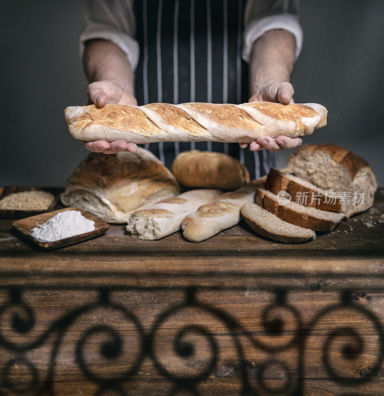面包师在传统面包店的木桌上提供法棍面包