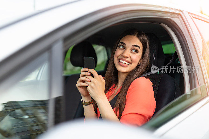 漂亮的年轻女子微笑和使用手机触摸车内屏幕旅行。现代概念的搜索和联系朋友时，你离开。智能手机的日常使用