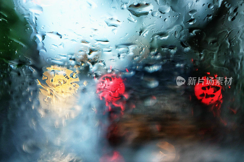 城市交通尾灯在街道上透过雨水条纹的湿挡风玻璃