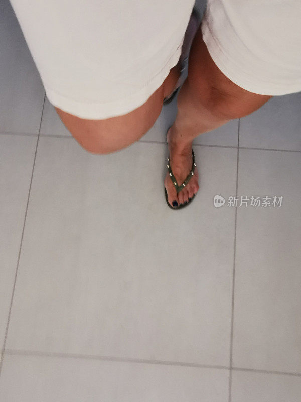 穿着时尚的人字拖鞋穿着短裤在室内行走的资深女性的脚