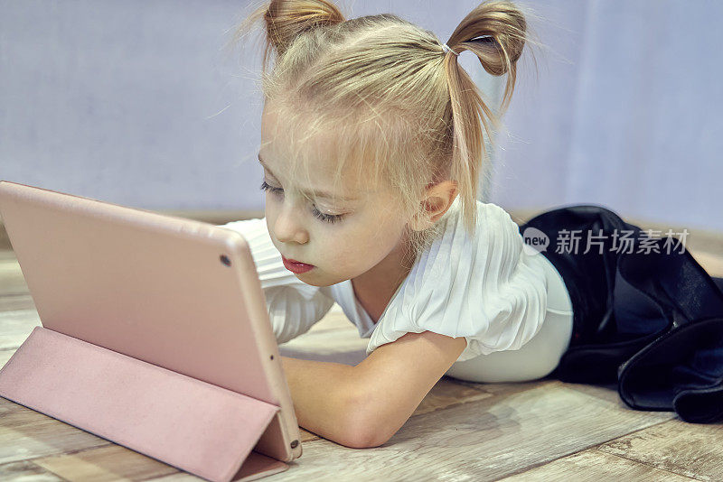 可爱的小女孩看着平板电脑上舞蹈课