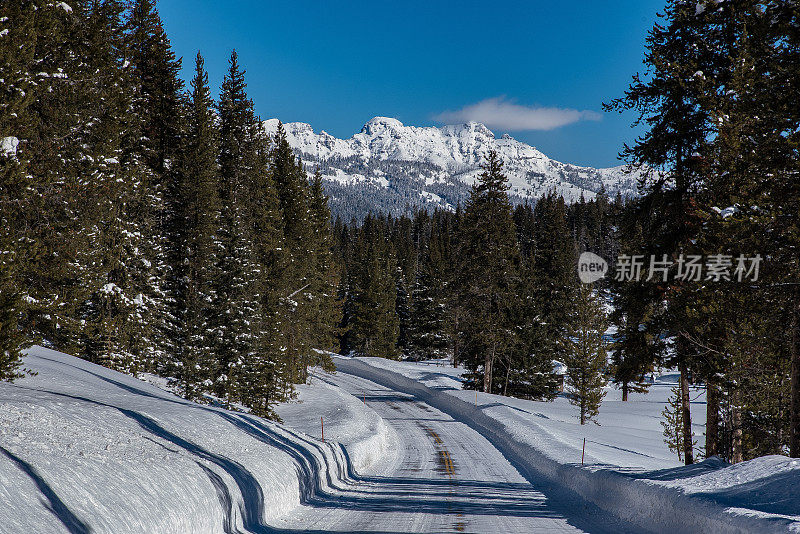 高速公路穿过白雪覆盖的树木和白雪覆盖的山脉