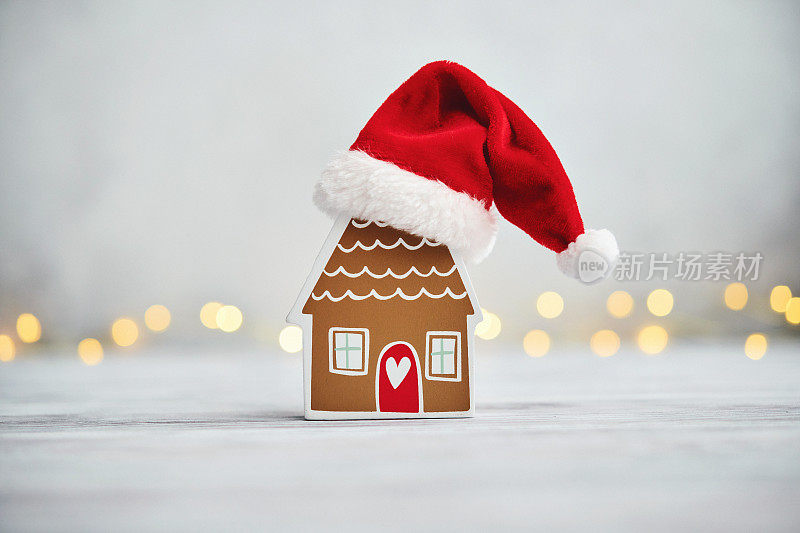有圣诞背景的小姜饼屋戴着圣诞老人的帽子