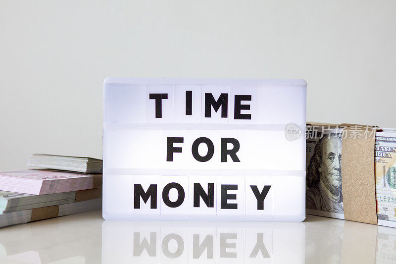 金钱时间概念与文字灯箱在家庭办公室。