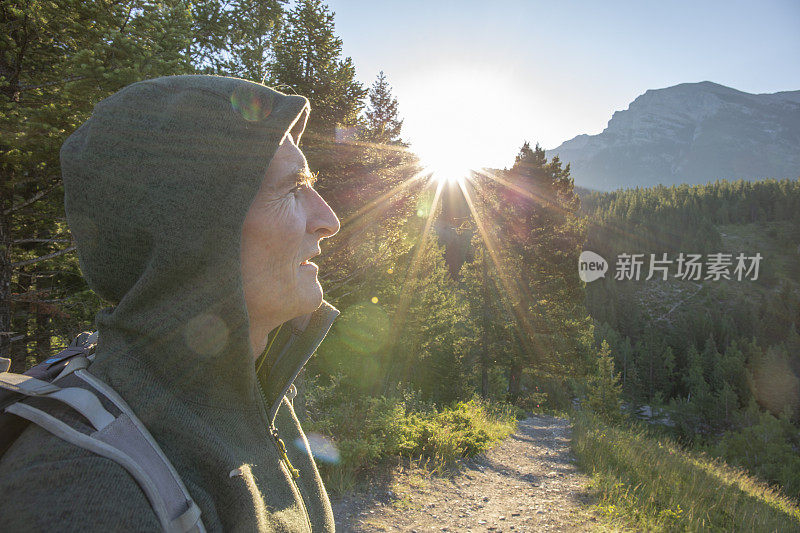 成熟的徒步旅行者穿着连帽衫看日出的山