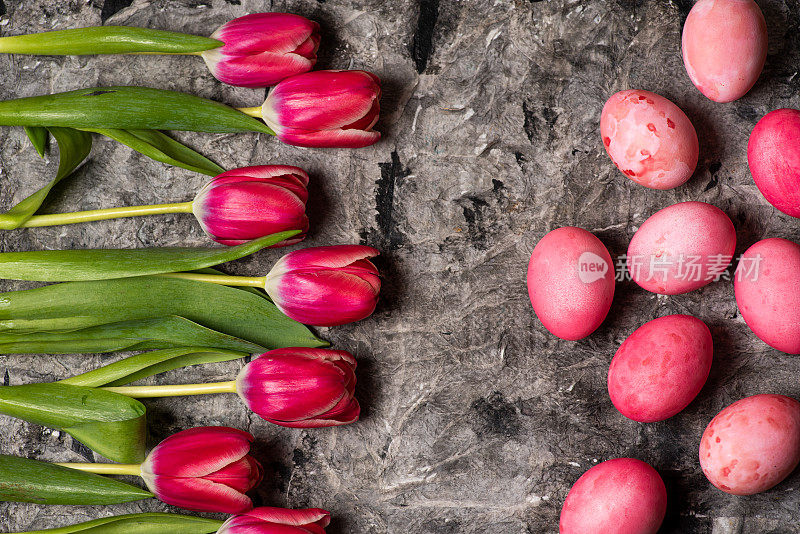 复活节彩蛋与红色郁金香花排列平放在木桌上