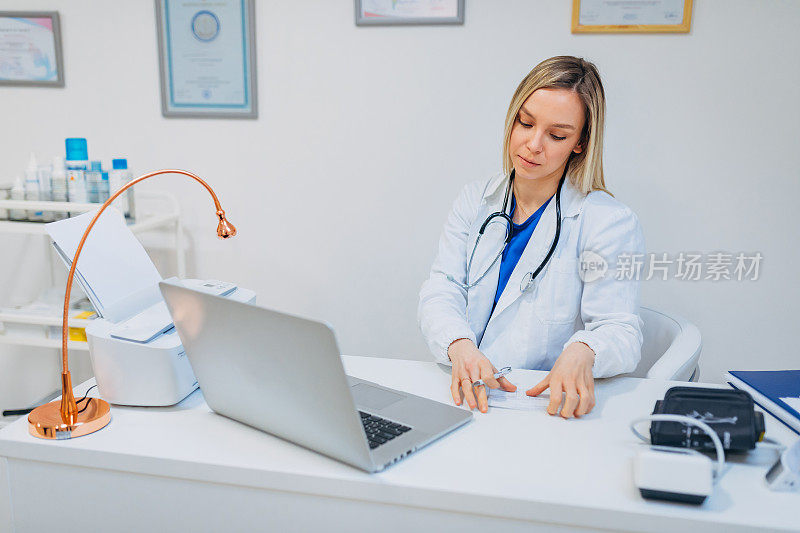 女医生，记录病人的症状，同时通过笔记本电脑进行网络会议，使用远程医疗作为一种新的常态