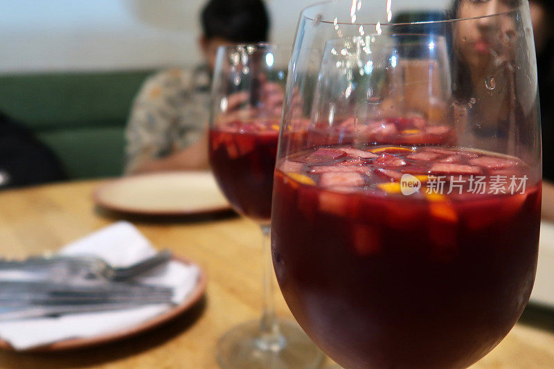 在餐厅的场景中，用红酒杯盛着桑格利亚汽酒(红酒、橙汁、白兰地、切碎的水果和糖)，聚焦前景