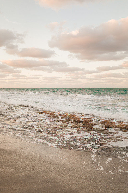 彩色天空在一个岩石海滩日落在木星，佛罗里达州在2021年3月