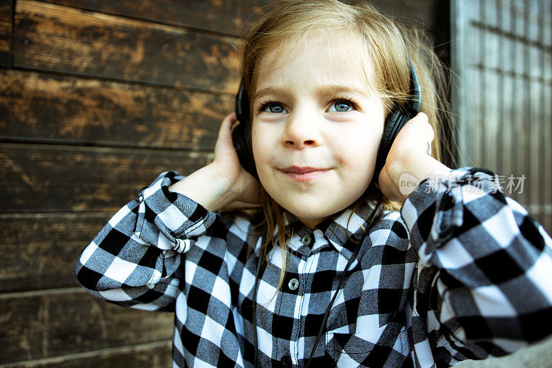 可爱快乐的小女孩戴着耳机听音乐