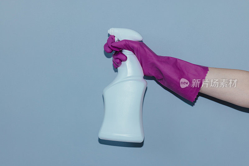 女性手握紫色橡胶手套，手持白色喷雾瓶