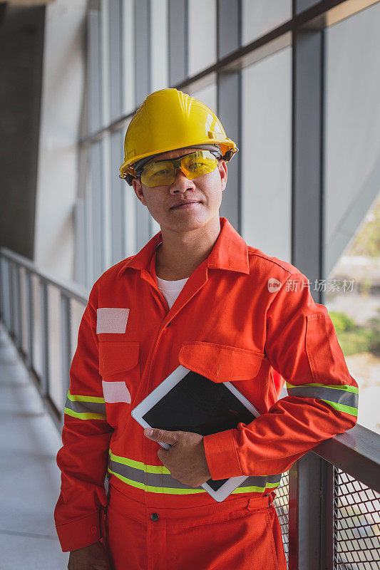 亚洲建筑或电子工程师的肖像，戴安全帽，穿着安全外套在施工现场