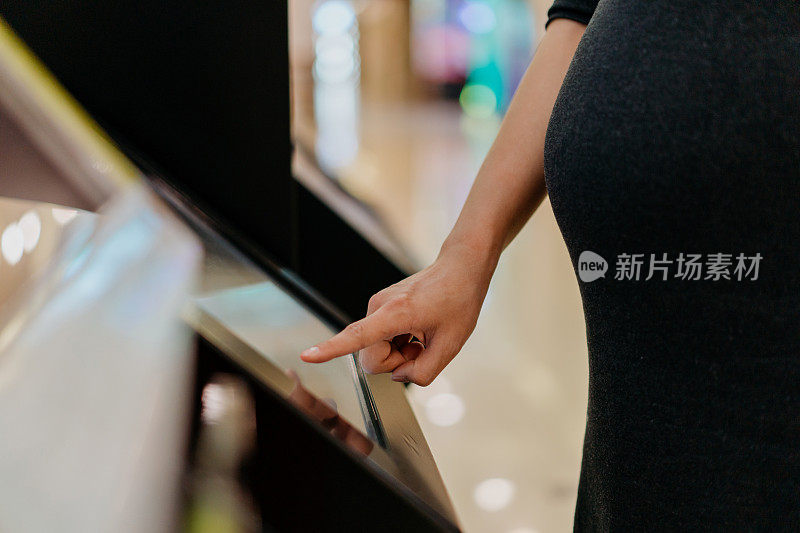 孕妇在购物中心使用触屏售货机