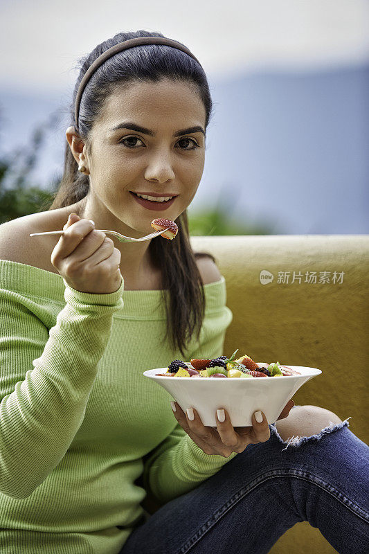 特写的一个西班牙可爱的年轻女人吃水果沙拉在户外午餐