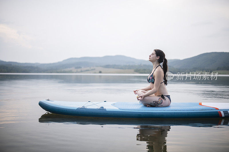 年轻女子在冲浪板上冥想