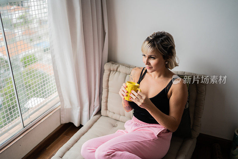 女人在家边看边拿着杯子