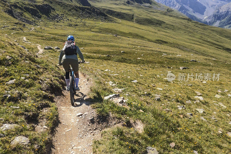 女人沿着阳光明媚的自行车道骑山地车