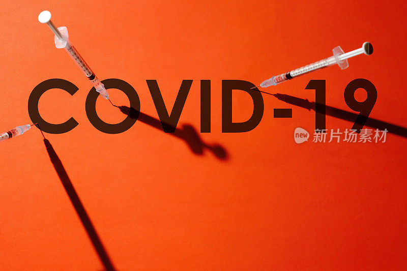 注射器上的针头刺穿单词COVID-19中的字母“o”和其他字母的中心。