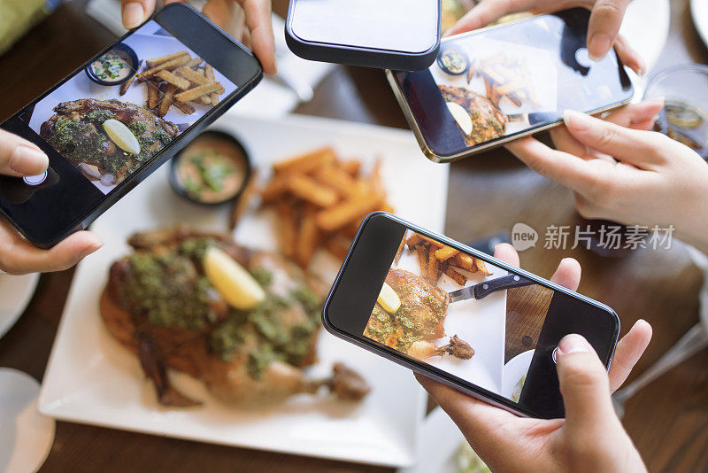 一群朋友在饭前用智能手机拍照。前视图。