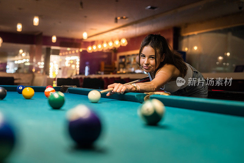 一个欢快的年轻女子在酒吧里打台球