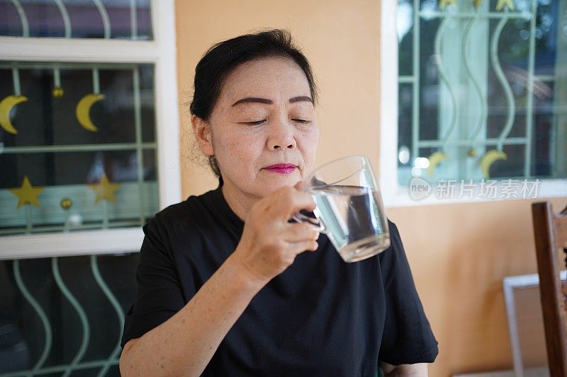 一位年长的妇女正在喝水。