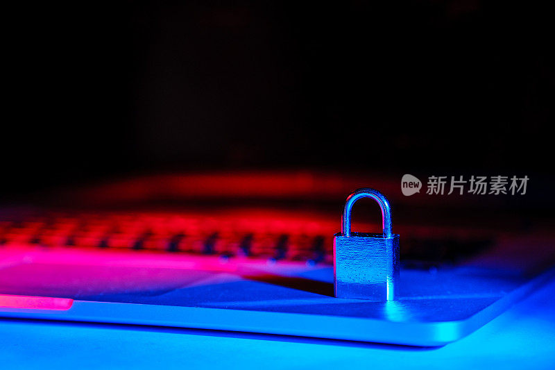 笔记本电脑上的挂锁被蓝色和红色的光照亮。网络安全对于网上购物和电子商务至关重要。副本的空间。