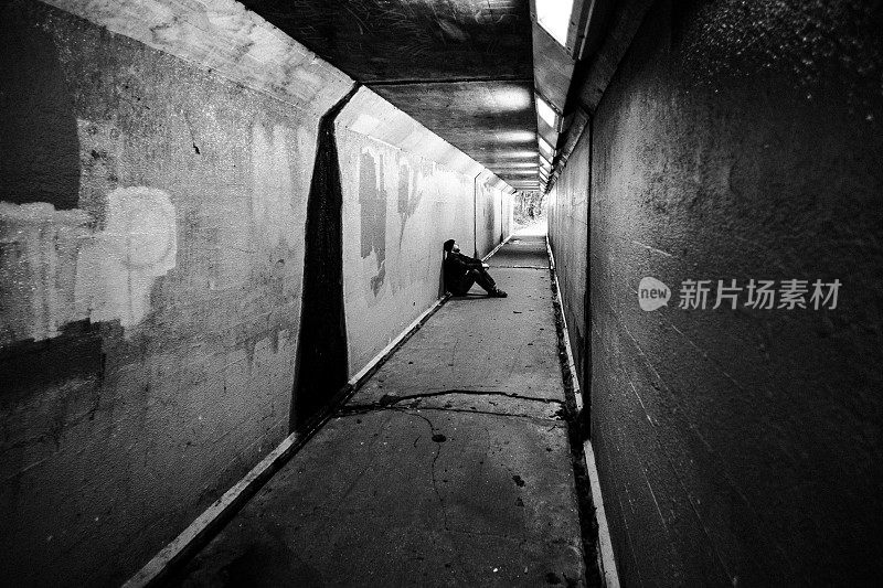 无家可归的人坐在寒冷黑暗的地铁隧道里