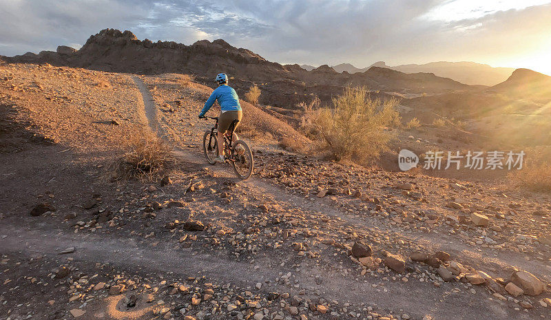 女山地自行车手在日出时沿着沙漠小路行进