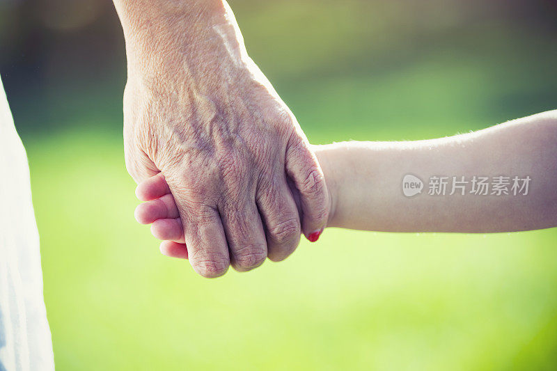 祖父母牵着孩子的手。