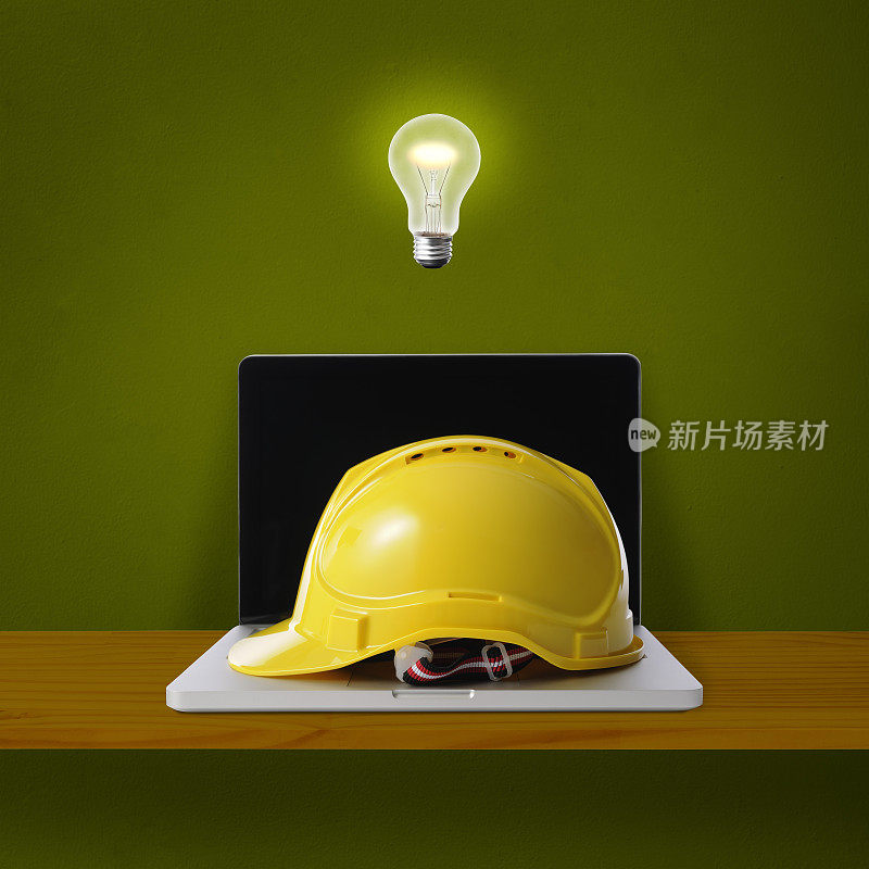 灯泡在半空中发光的笔记本电脑与黄色的安全帽