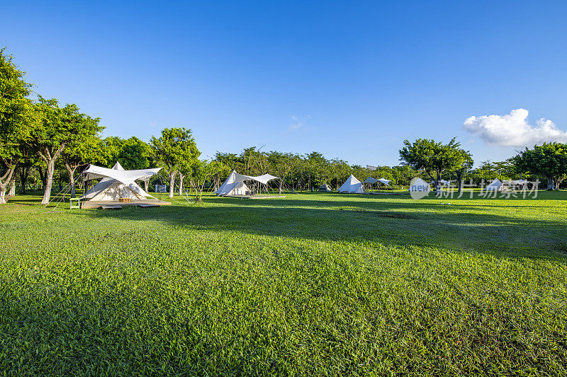 清晨，阳光照在公园草坪上的露营帐篷上