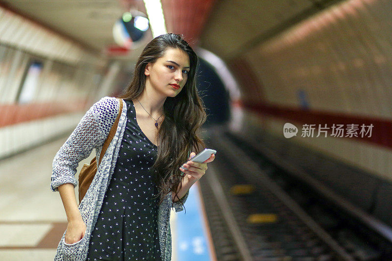 年轻女人看电话，乘客在车站等地铁，旅游女人在城市旅行