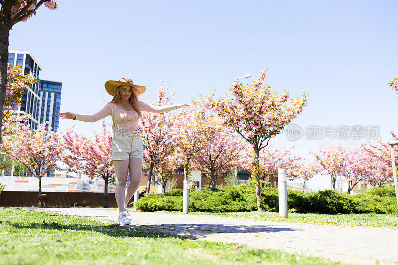 美丽的女人附近樱花盛开的树。春天的概念