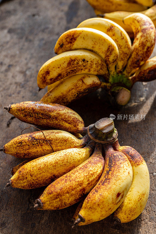 一串成熟的本地有机新鲜香蕉准备出售后陈列在桌子上的照片