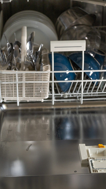 洗碗机与干净的盘子特写。厨房电器。盘子，叉子和杯子在洗碗机里。