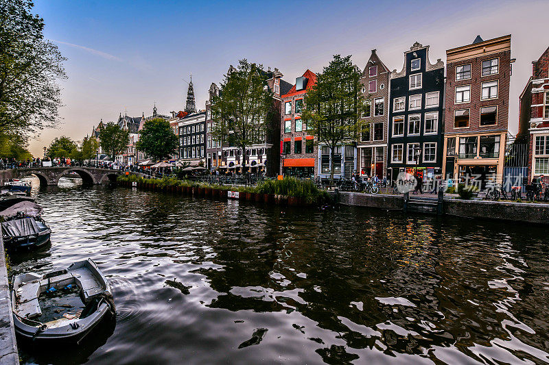 阿姆斯特尔河运河繁忙的夜晚，荷兰阿姆斯特丹的人们在河边散步