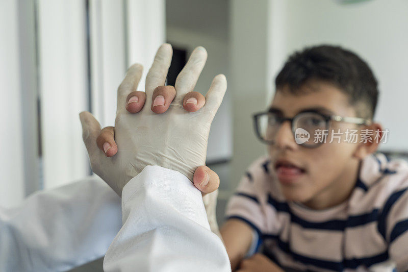 在残疾儿童健康中心，一名物理治疗师正在为一名年轻残疾男孩进行手部治疗。开展残疾人综合康复活动。