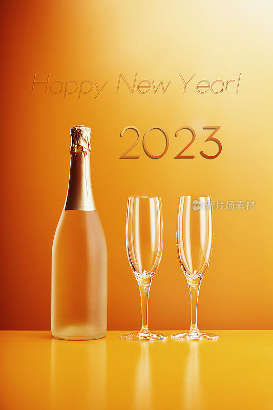 未打开的气泡酒瓶和两个空香槟杯，在橙色的背景下写着2023年新年快乐的文字