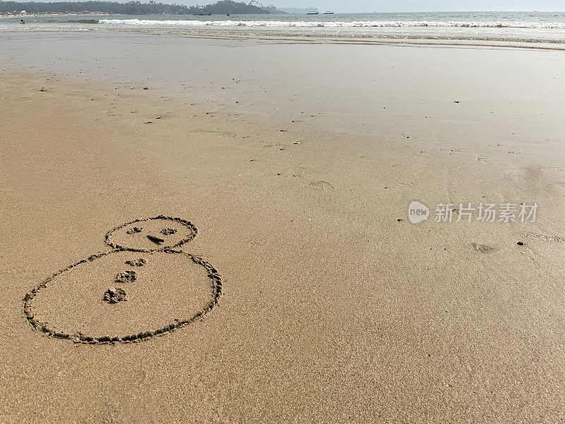 图像的雪人木棍鼻子画在沙滩上的阳光沙滩边的水，海洋背景，重点在前景，复制空间，圣诞节在南半球的概念