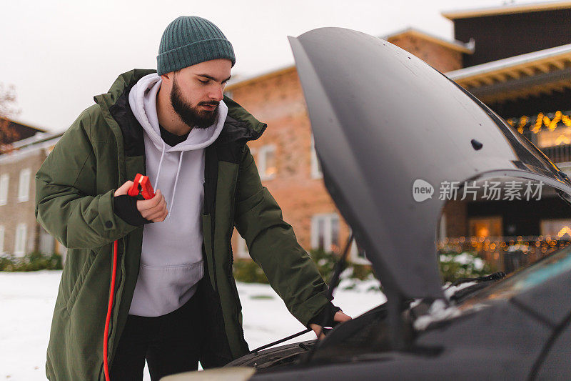 穿着冬装的大胡子男子在冬天跳着启动他的汽车