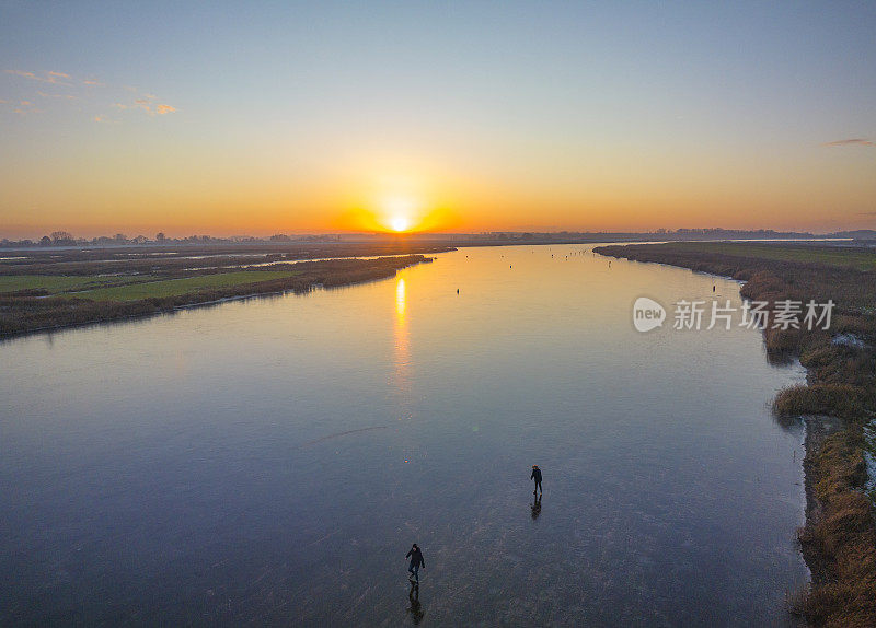 在美丽的冬日夕阳下，荷兰的湖面上滑冰