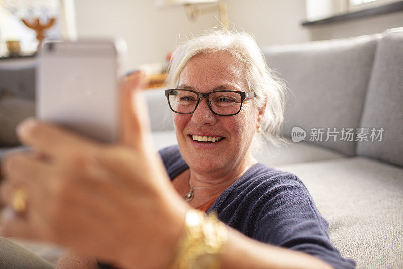 一位老年妇女在一所房子的客厅里用手机