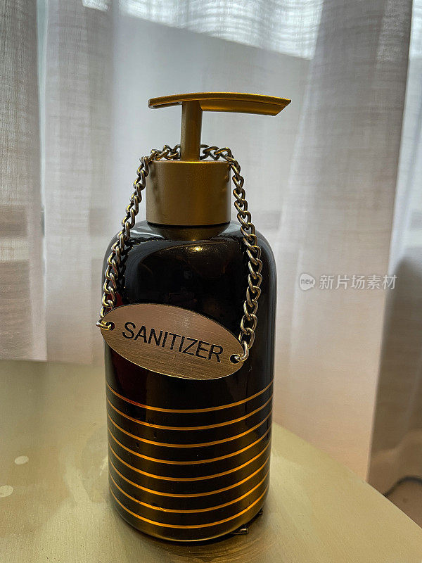 酒店房间的桌面图像，黑色泵消毒分配器瓶洗手，卫生，窗帘背景，重点在前景