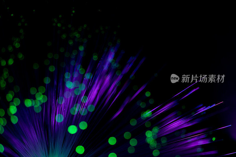 发光光纤。梦幻般的背景照明霓虹灯紫色光纤线和发光的绿色散景在黑色。