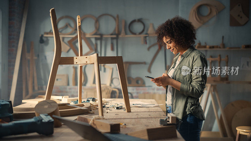 产品设计师正在用智能手机拍摄木椅项目照片。有创意的黑人女性在网上给同事发照片，寻求反馈和评价。
