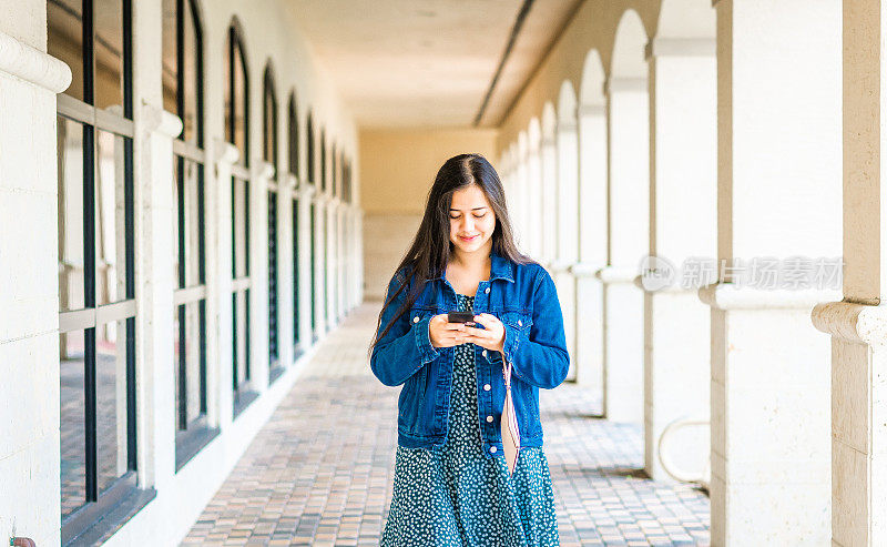 年轻的亚洲女大学生在户外使用手机