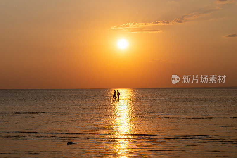 两个人在夕阳下的海边散步。浪漫的约会。条