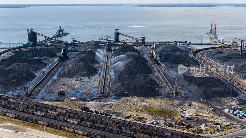 煤炭在港口码头运输后要加水，防止空气污染。湿煤堆和货运作为纽波特纽斯的全球业务，弗吉尼亚州。鸟瞰图