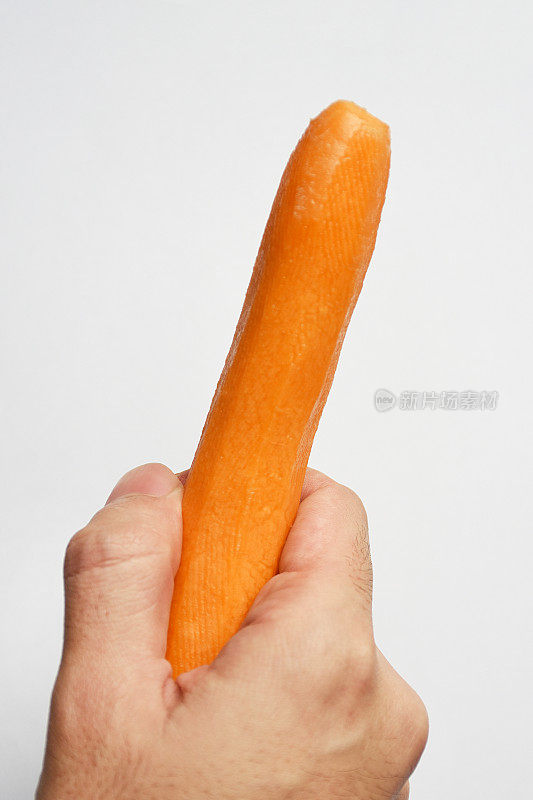 手拿剥了皮的新鲜胡萝卜在白色的背景