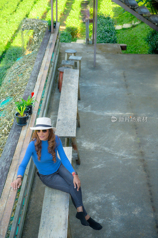 一名亚洲女游客在清迈省茶园的木凳上休息